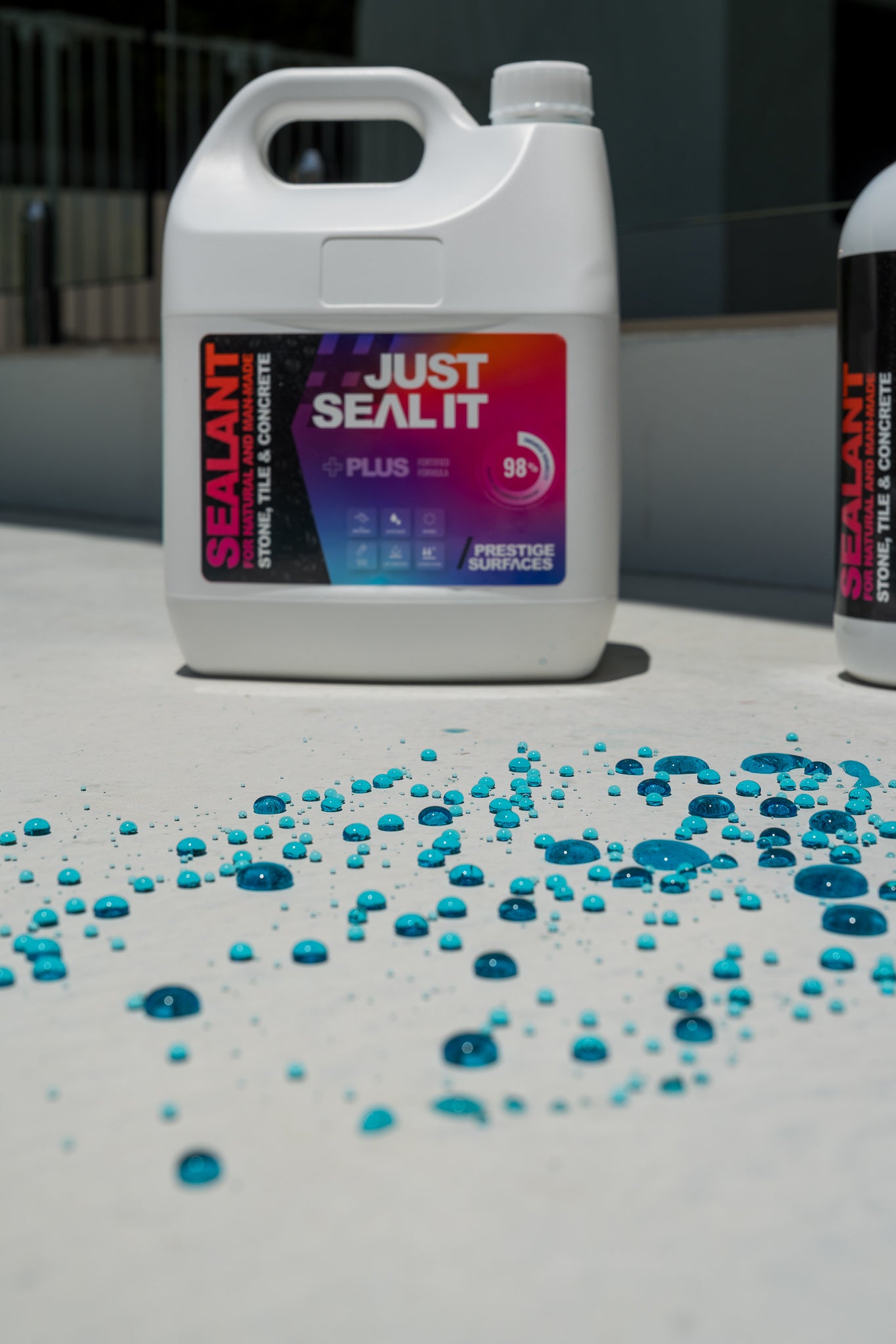 Just Seal It Plus 4L container with blue dye water beading on sealed outdoor surface
