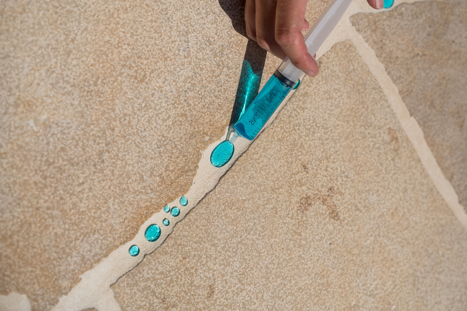 Blue water beading on sealed grout lines — demonstrating water repellency after sealing